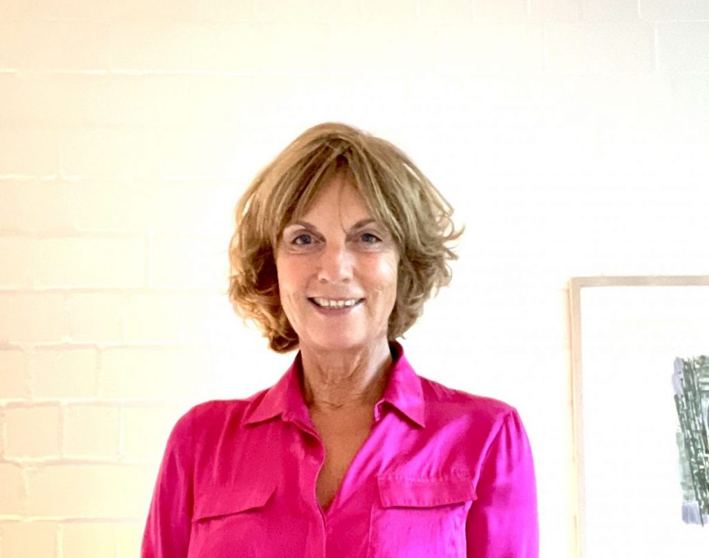 Christine Brummer wearing a pink shirt and smiling at the camera